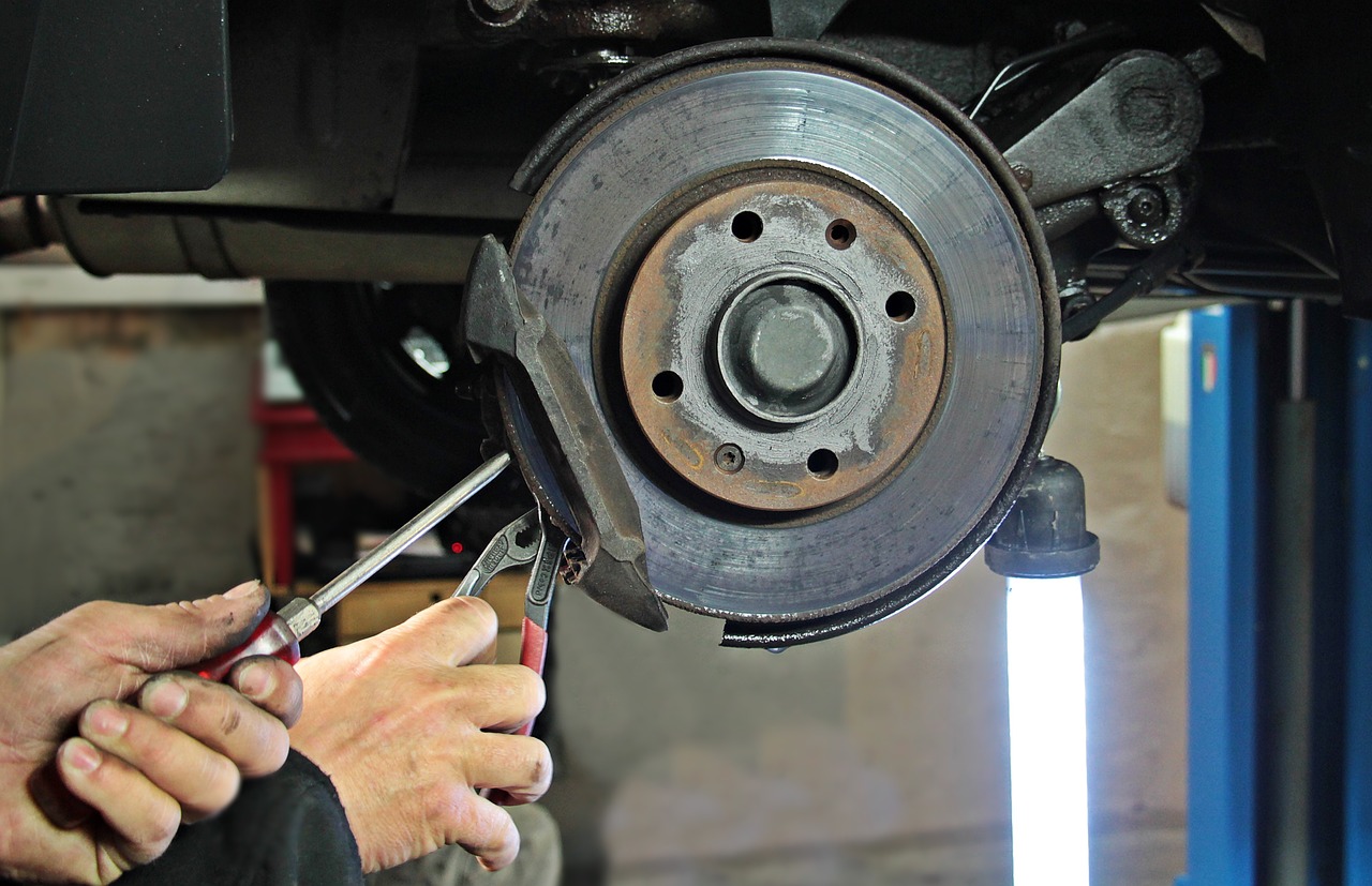 an auto-mechanic fixing the brake pads of a car