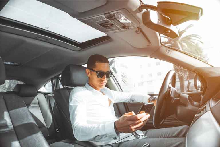 a man sitting on the driver's sit while using his android phone