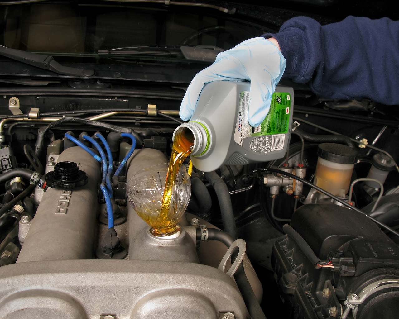 an  auto mechanic pouring oil into the engine of the car